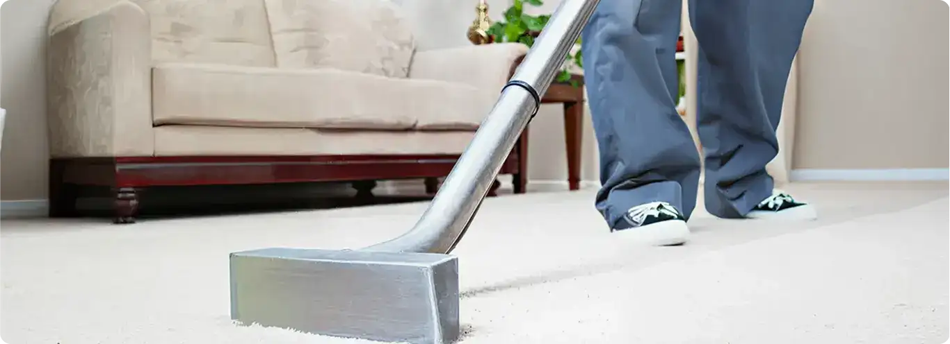 Carpet cleaning technician using a hot-water extraction wand on a light-colored carpet in a living room, Ogden, UT.