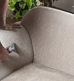 Professional upholstery cleaner deep-cleaning a fabric sofa with a handheld extraction tool and hose Ogden, UT.